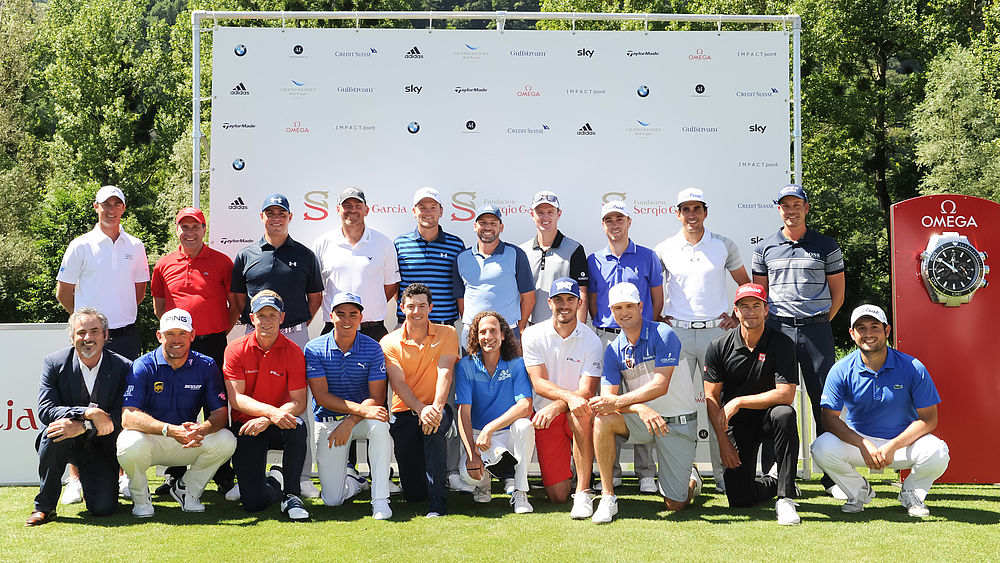 Eine Gruppe der besten Golfer der Welt in legerer Kleidung posiert an einem sonnigen Tag im Freien, mit einem Sponsor im Hintergrund und einer roten Uhr im Hintergrund, die Teamwork und Sportlichkeit vermittelt.